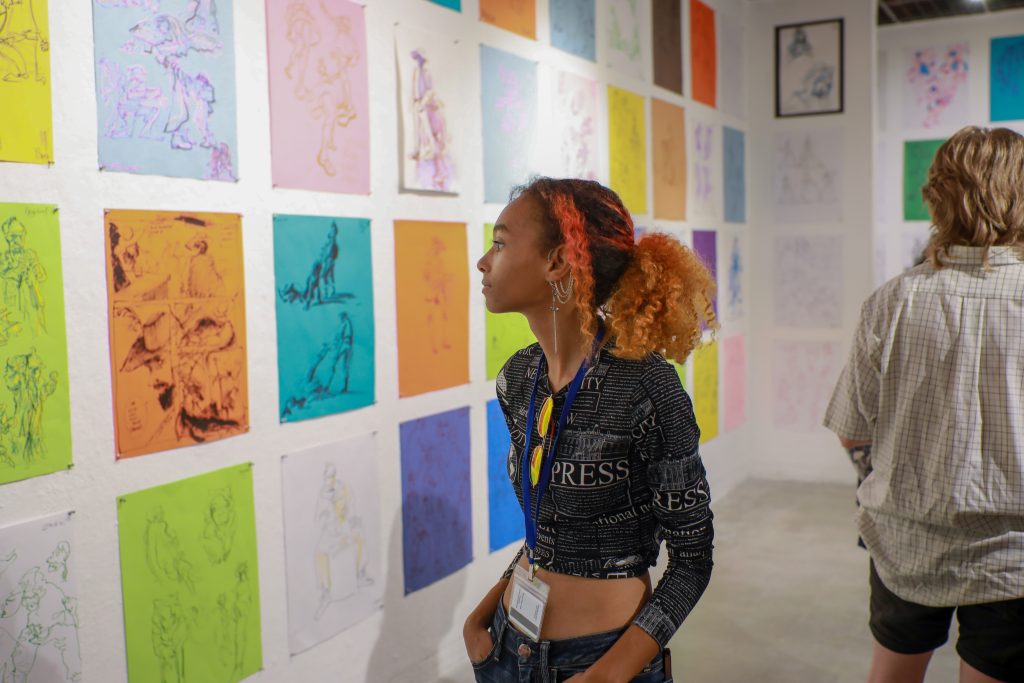 Student looking at gallery wall and life drawing.